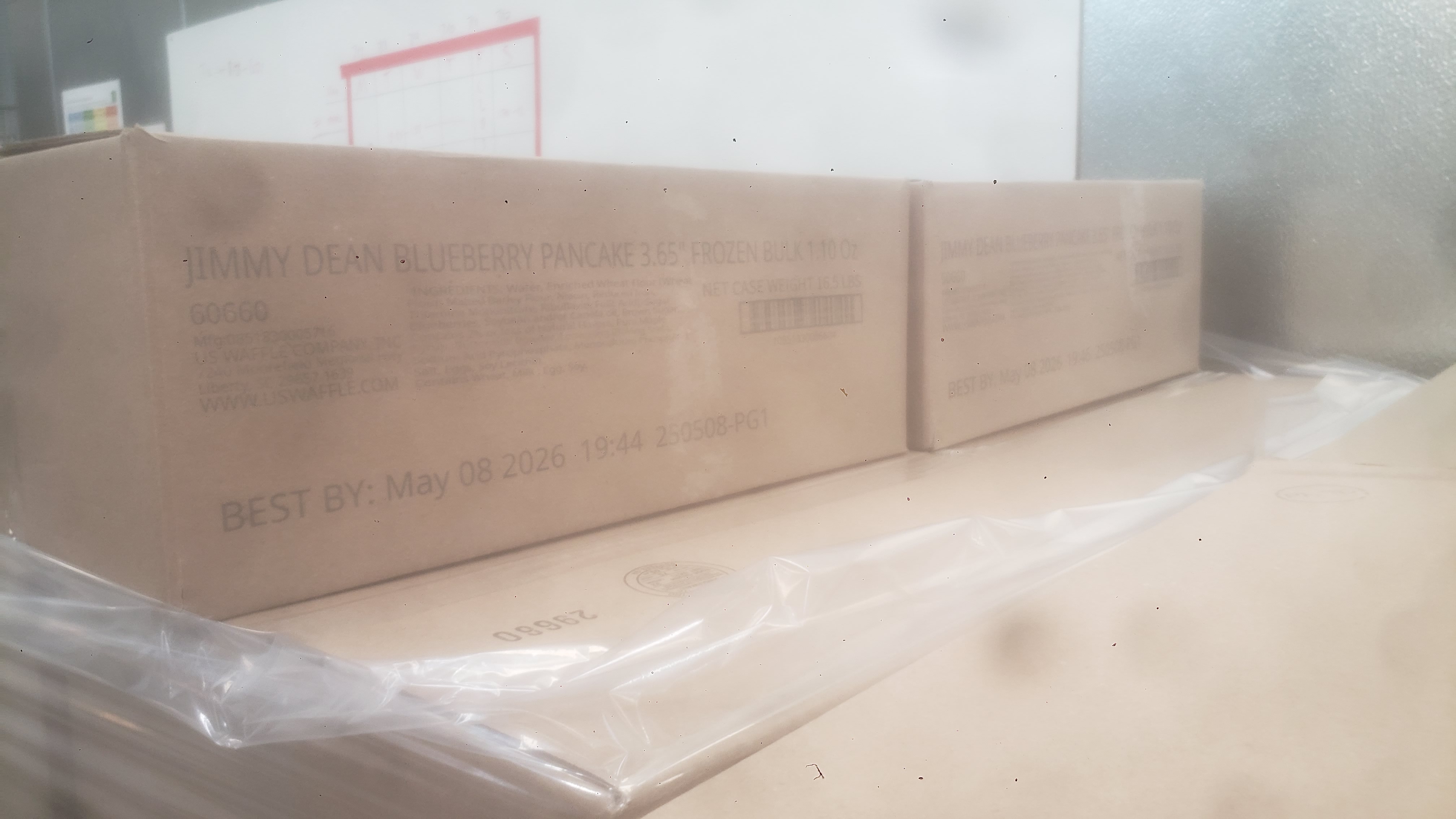 Cardboard boxes of frozen blueberry pancakes wrapped in plastic on a pallet.